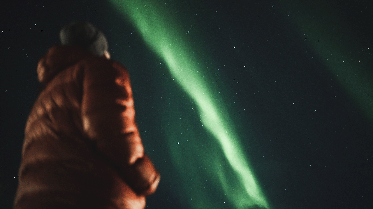 Mies katsoo kuvassa vihreitä revontulia